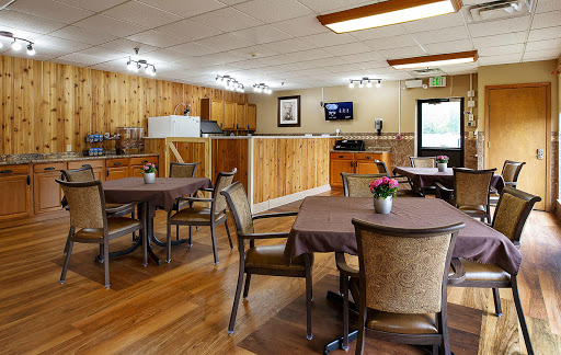 A cozy dining area featuring wooden decor, tables set for guests, and a television in the background.