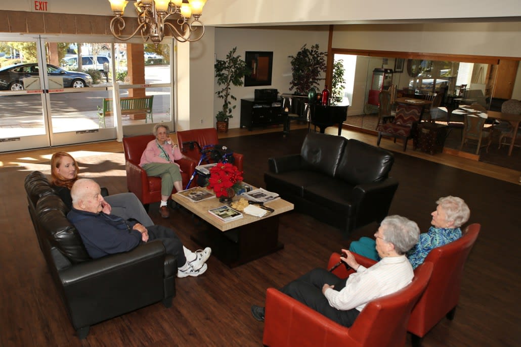 A group of senior citizens seated in a lounge area, engaging in conversation.
