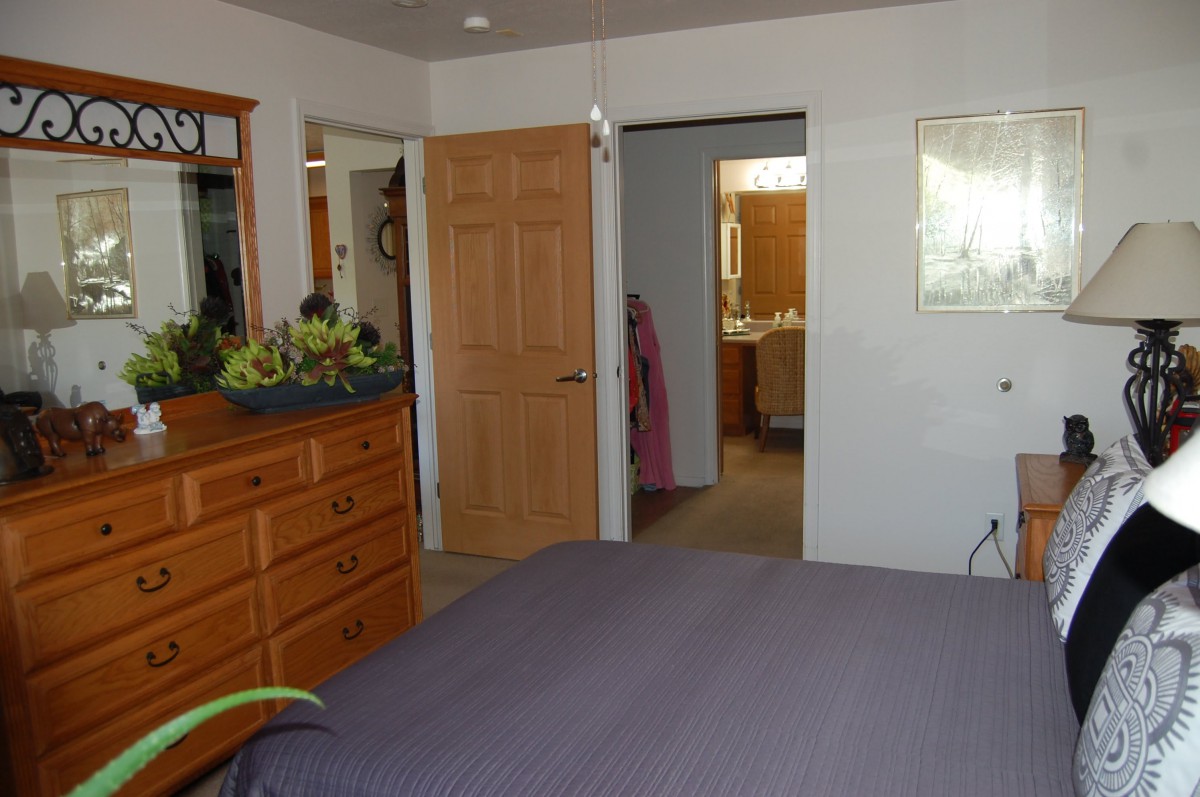 A cozy bedroom with a wooden dresser and an open door leading to a bathroom.