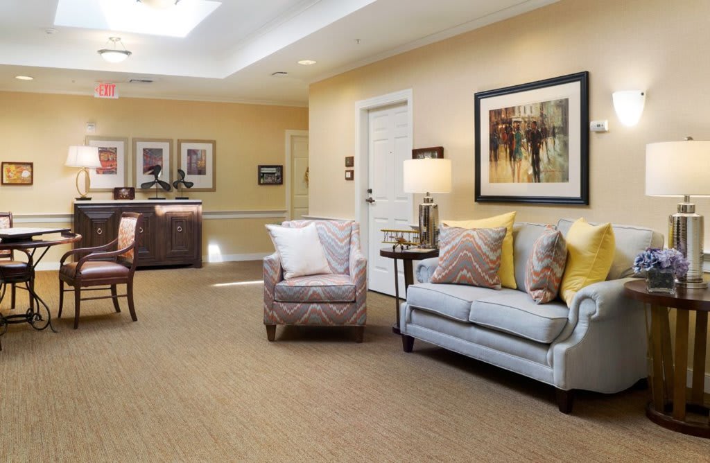 A cozy and well-decorated living room with a sofa, armchair, and wall art.