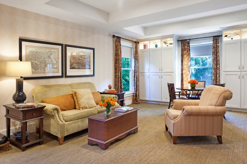 A cozy and elegantly designed living room with comfortable seating, artwork, and a small dining area.