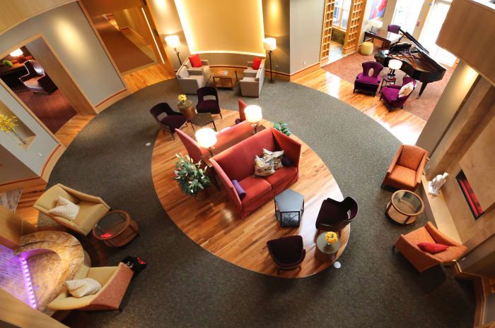 A modern hotel lobby with a cozy seating area featuring contemporary furniture and a wooden floor.