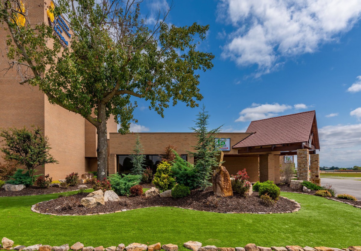 A landscaped garden with a building and clear blue sky.