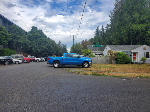 A blue truck parked on a quiet street surrounded by houses and greenery.