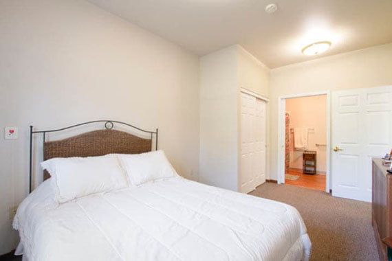 A minimalist bedroom featuring a bed with white linens and simple decor.