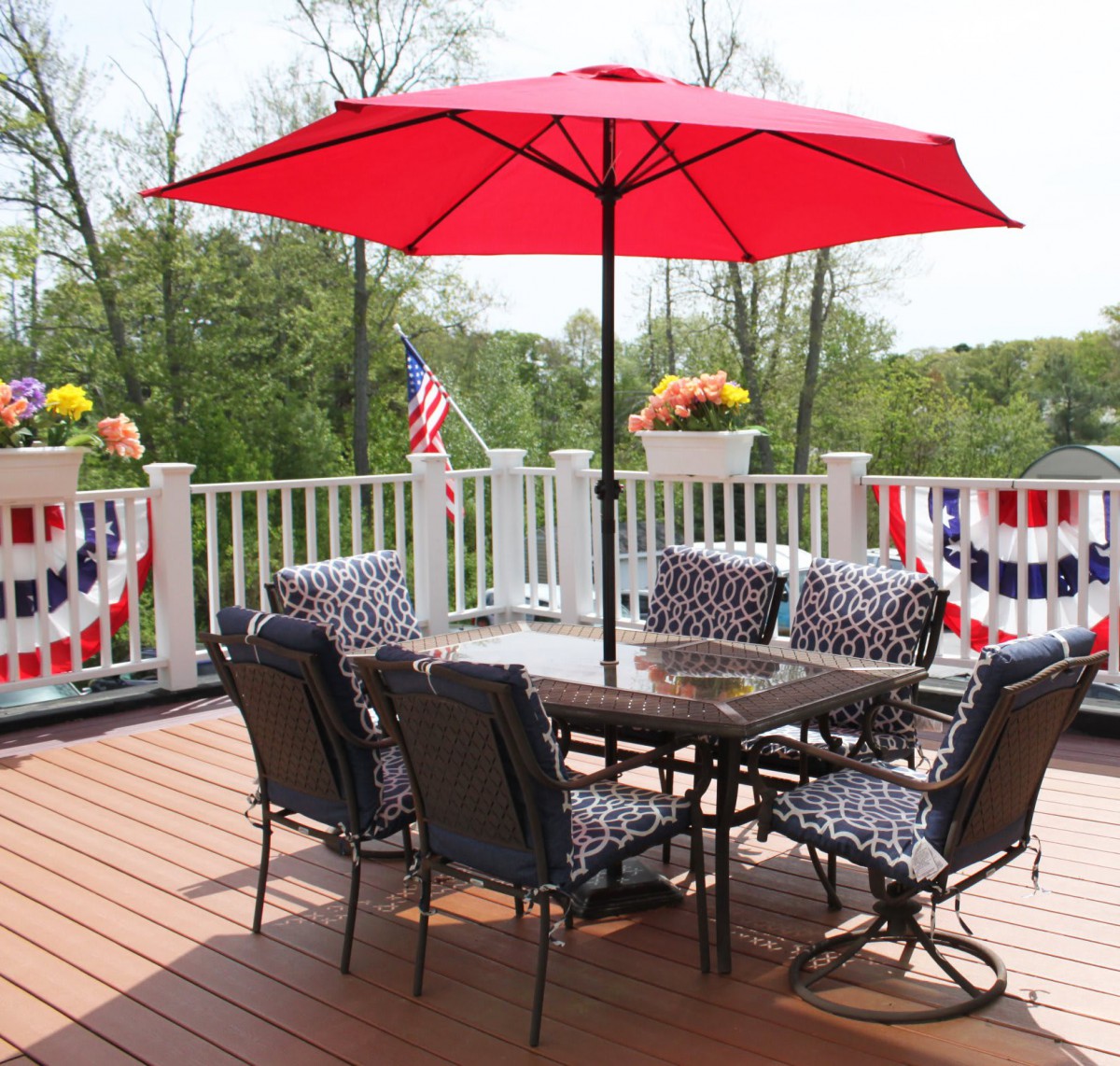 A cozy outdoor patio with a red umbrella and stylish furniture, adorned with festive decorations.
