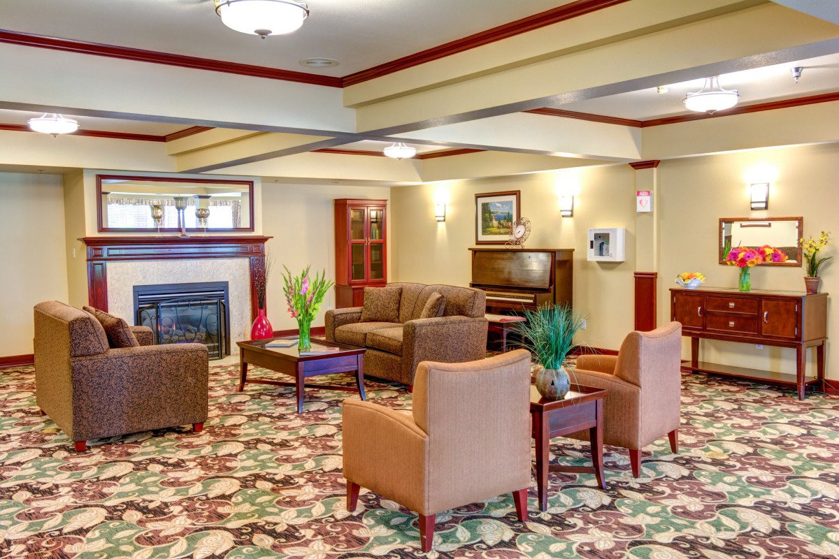 A cozy lobby area featuring sofas, armchairs, a coffee table, and a fireplace.