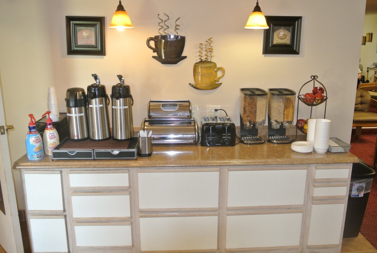 A well-organized breakfast bar featuring coffee dispensers, a toaster, and cereal dispensers.