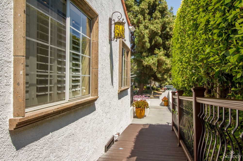 A sunny pathway beside a house with windows and a decorative lantern.