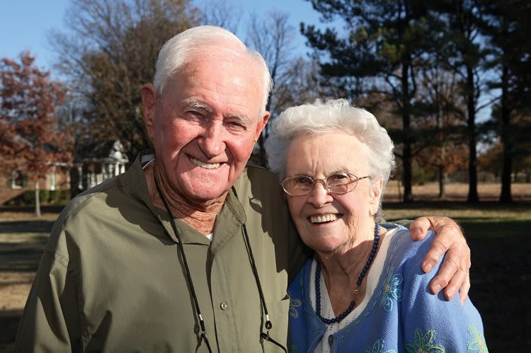 An elderly couple smiling and enjoying a day outside.
