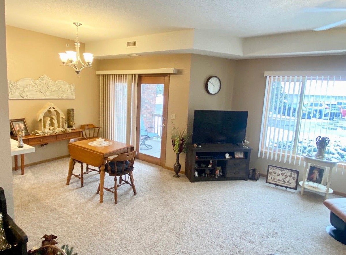 A cozy living room with a dining table, TV stand, and carpeted flooring.