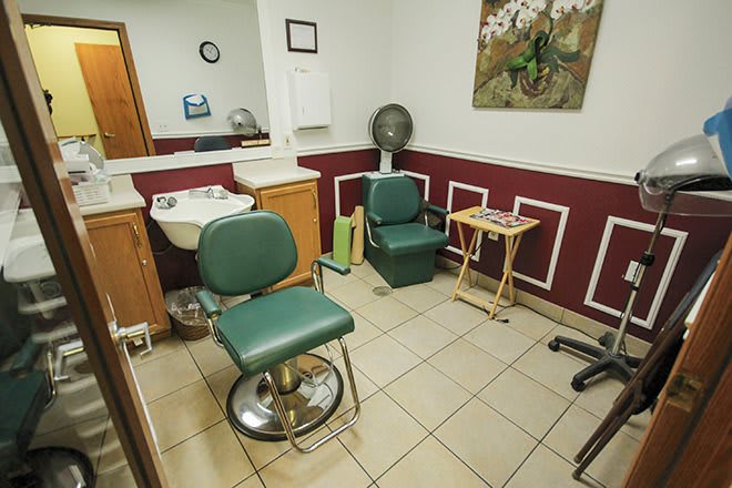 A cozy barbershop interior featuring chairs, a sink, and a mirror.