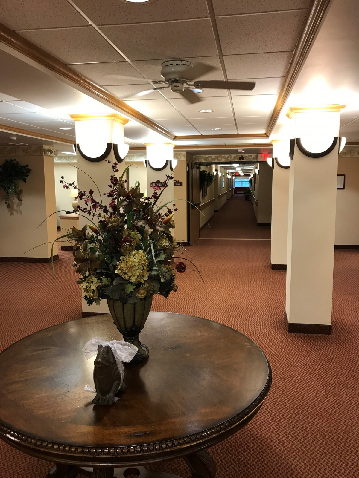 A well-lit hallway with a decorative flower arrangement on a round table.