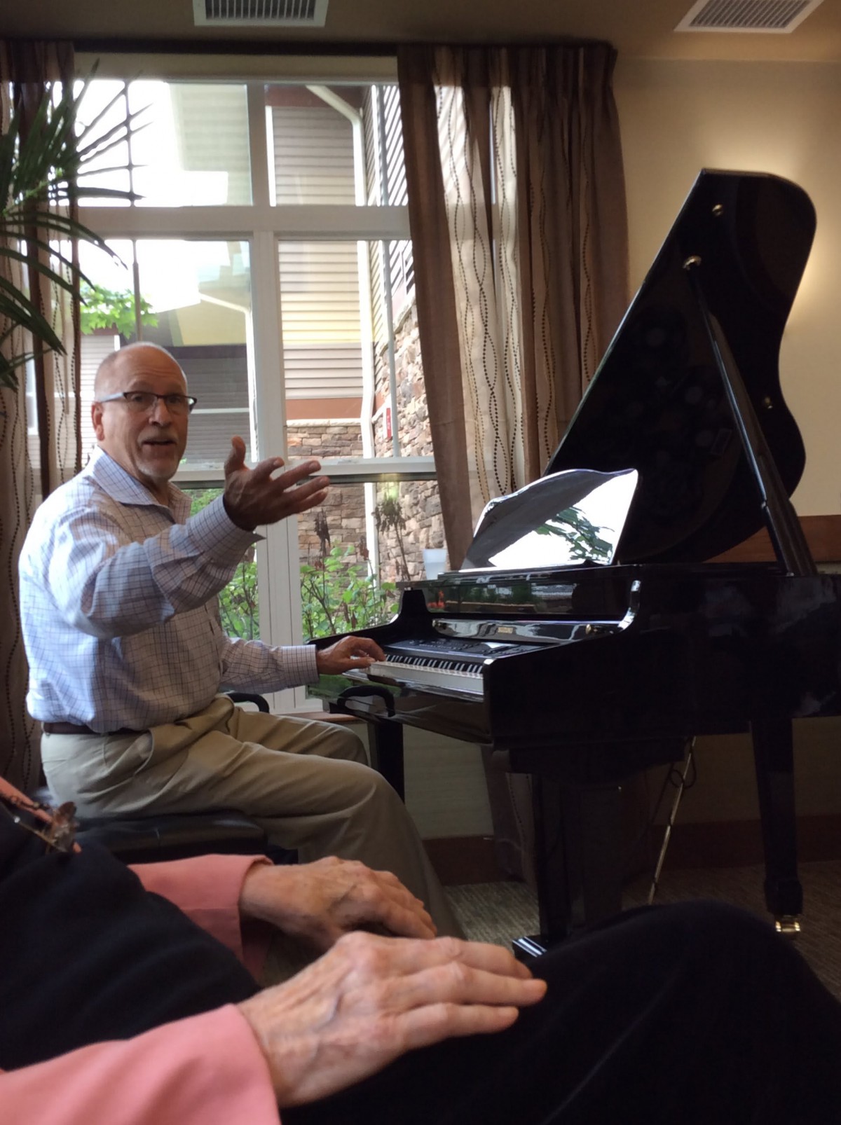 An elderly man playing the piano indoors.