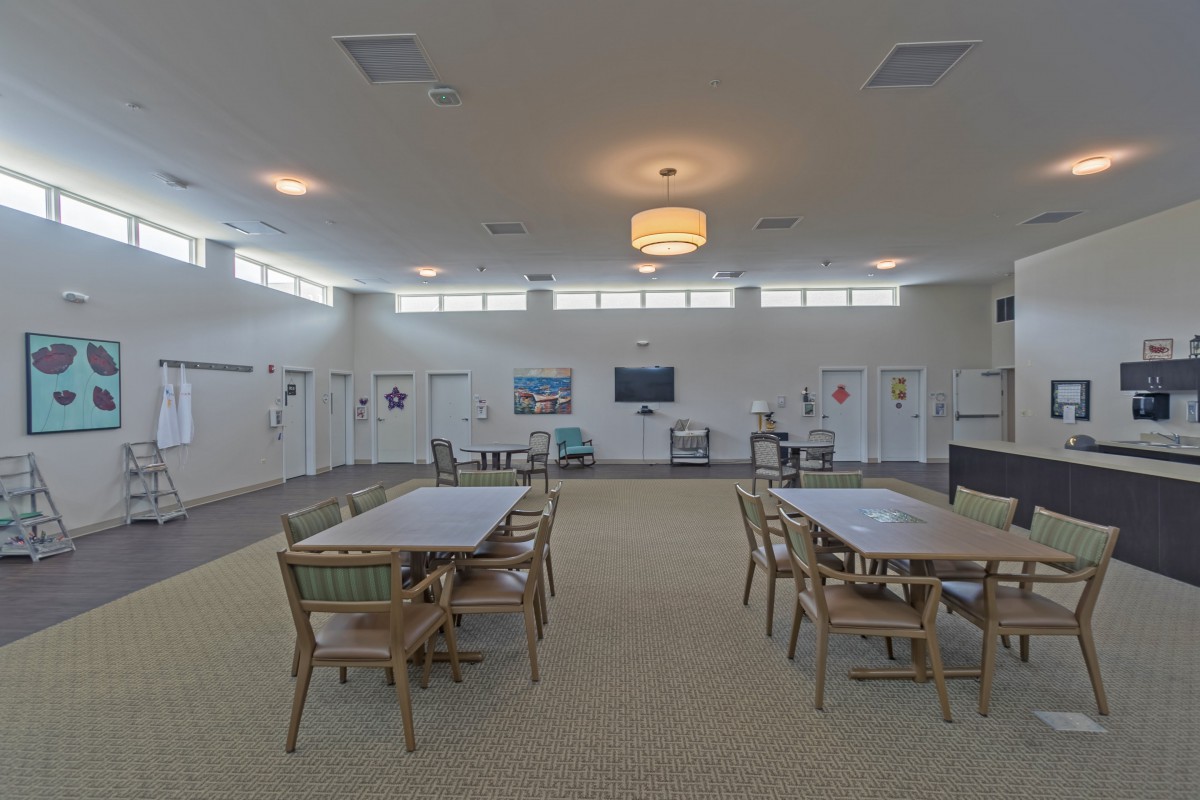 A spacious conference room with tables, chairs, and a television on the wall.