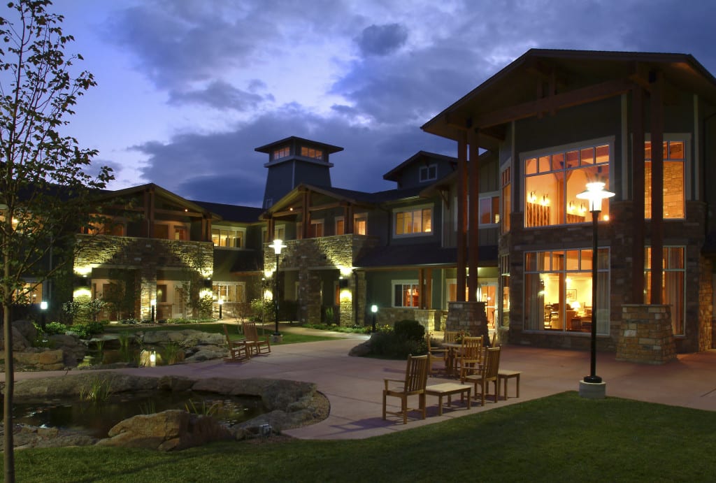 A luxurious house illuminated at night with a landscaped garden.