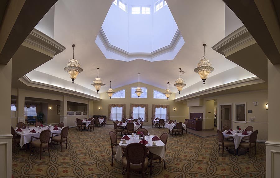 A spacious dining room with elegantly set tables and a large skylight.