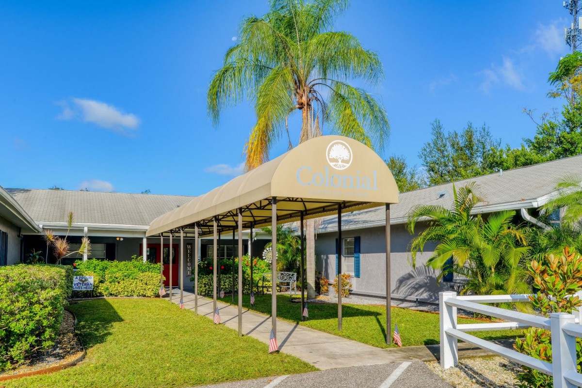 A sunny day outside a building with a canopy entrance and palm trees.