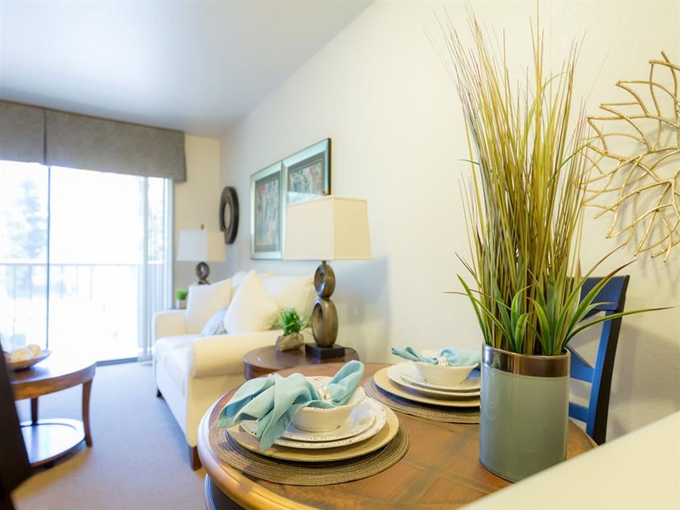 A modern living room with a neatly set dining table and decorative plants.