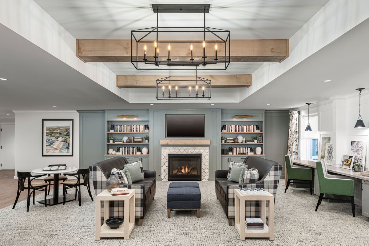 A cozy living room with elegant chandeliers, a fireplace, and built-in bookcases.