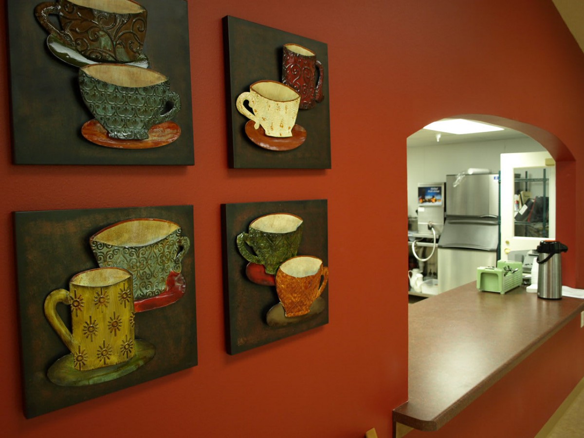 A cozy kitchen adorned with colorful coffee cup art on a warm red wall.