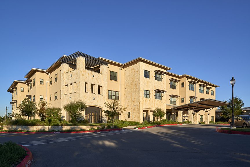 A modern multi-story building with stone facade under a clear blue sky.