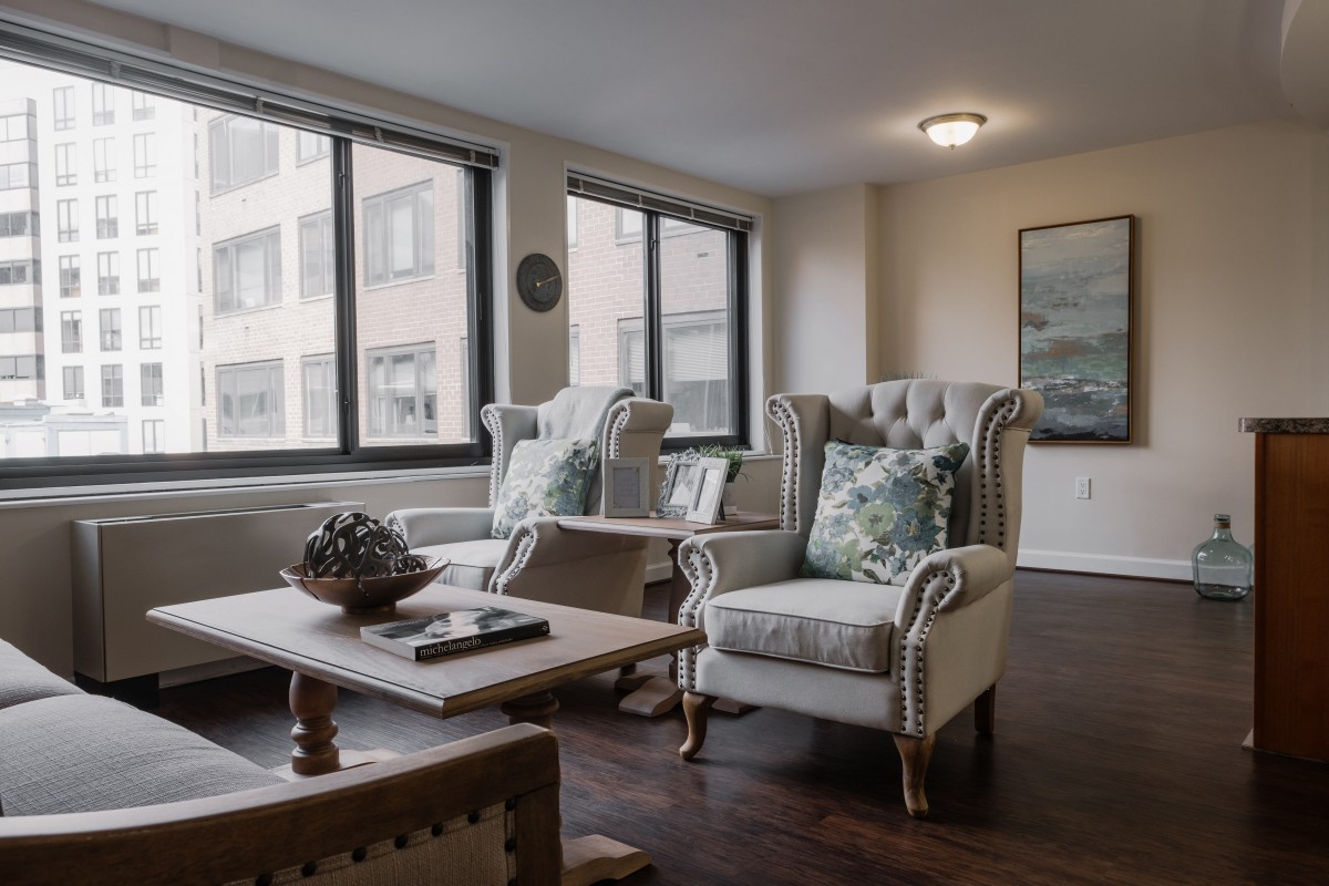 A cozy living room with elegant armchairs and a coffee table set near large windows.