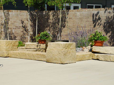 Outdoor garden area with stone benches and potted plants on a sunny day.