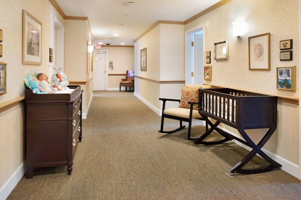 A well-lit hallway with carpeted flooring, decorated walls, and comfortable furniture.