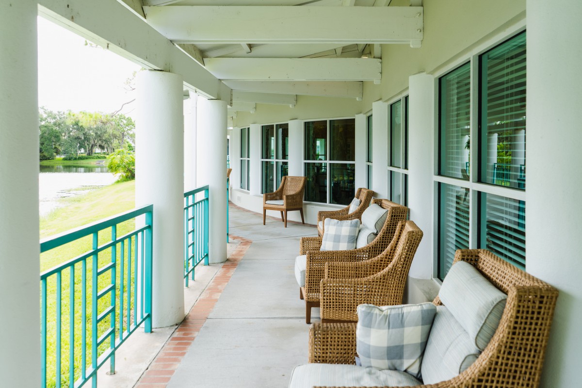 A peaceful veranda with wicker chairs and pillows, overlooking a green landscape.