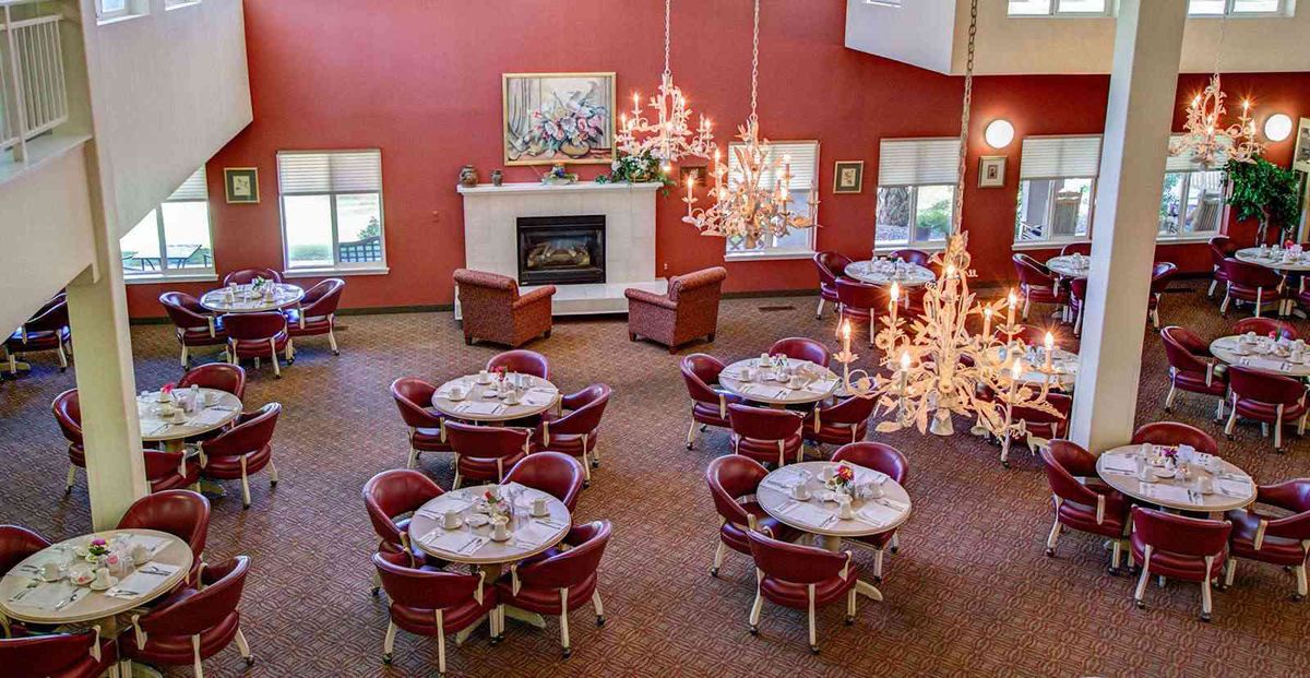 A spacious dining area with elegant chandeliers, red walls, and a cozy fireplace.