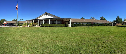 A charming rural house with a well-maintained lawn under a clear blue sky.