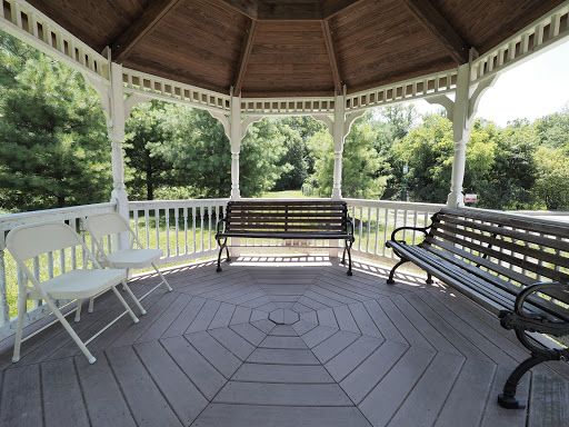 A serene gazebo surrounded by greenery, featuring multiple benches for relaxation.