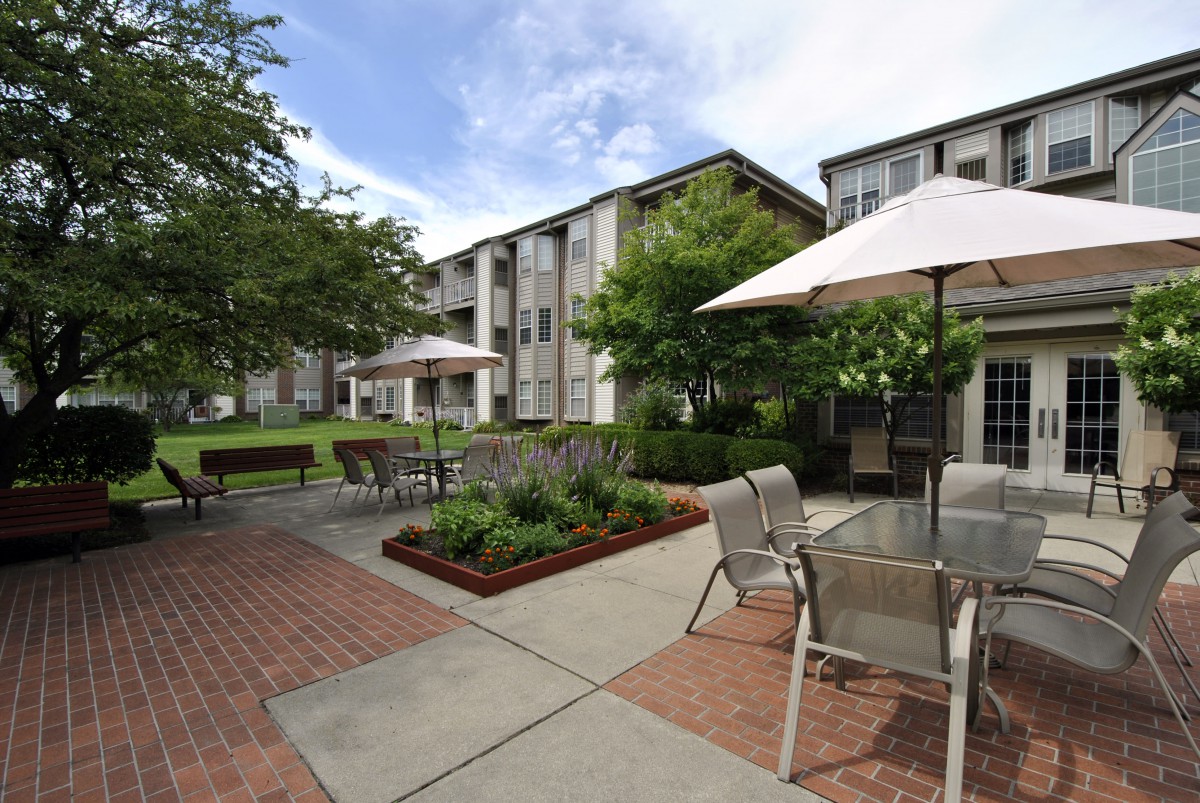 A serene courtyard in an apartment complex with outdoor seating and garden areas.
