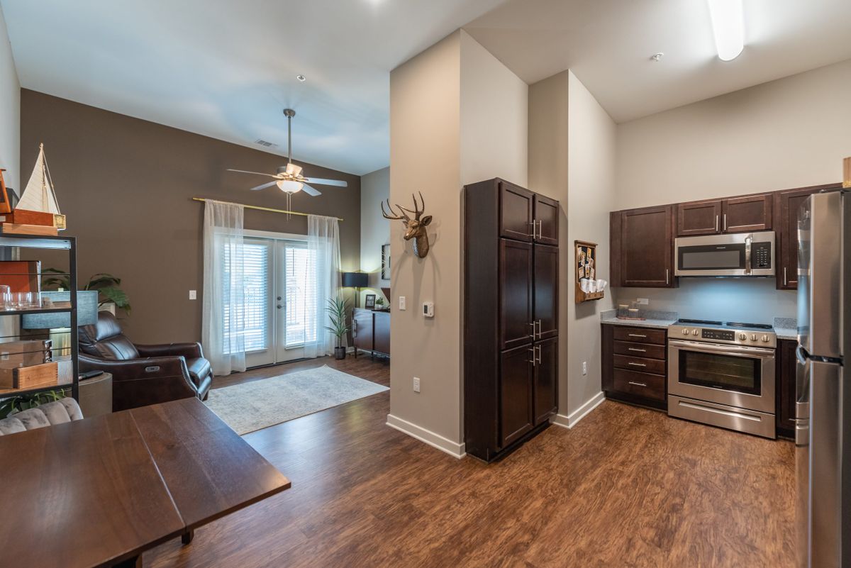A modern open floor plan featuring a kitchen and living area with high ceilings and hardwood floors.