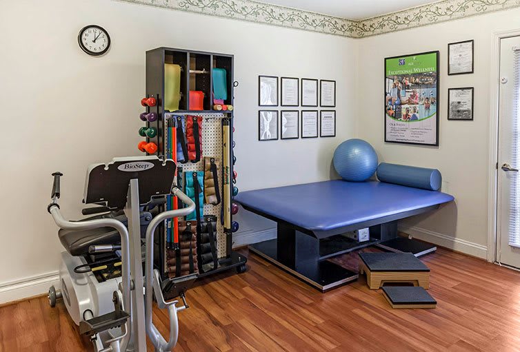 A rehabilitation room equipped with various exercise tools including a therapy table, yoga ball, and weights.