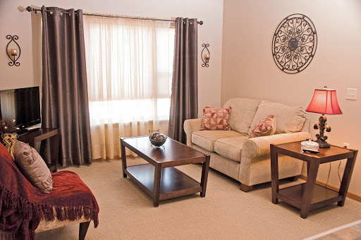 A cozy living room featuring a comfortable couch, wooden coffee table, and elegant curtains, creating a warm and inviting atmosphere.