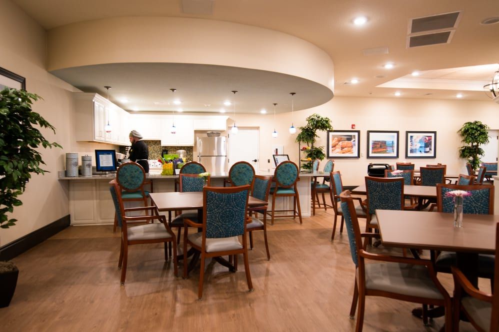 A cozy dining area with tables, chairs, and a view into the kitchen.