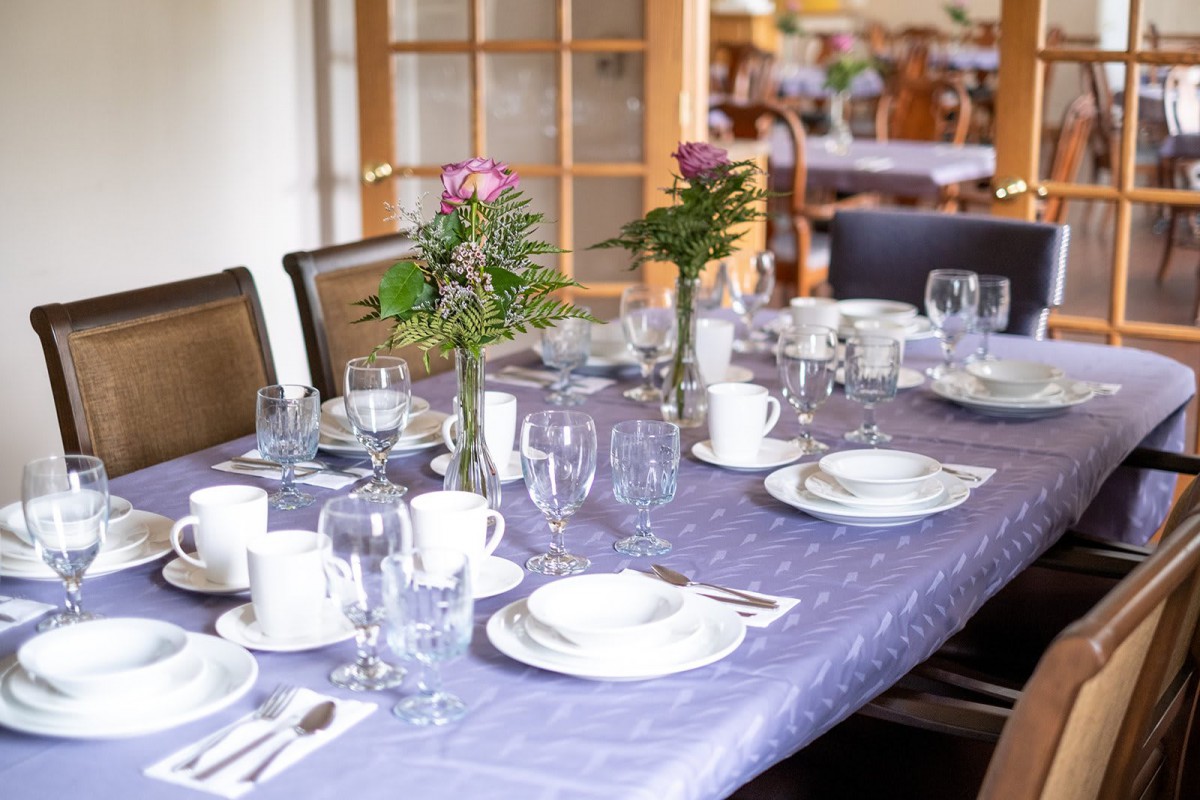A neatly set dining table with floral centerpieces and elegant dinnerware.