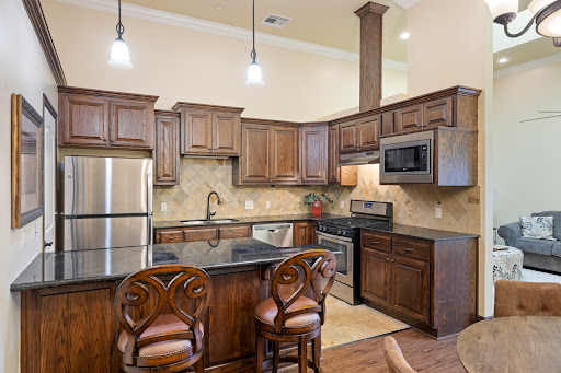 A stylish modern kitchen featuring wooden cabinets, stainless steel appliances, and a cozy seating area.