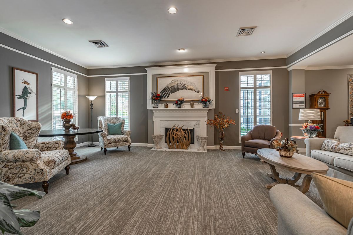 A cozy living room with elegant furniture and a central fireplace surrounded by large windows.
