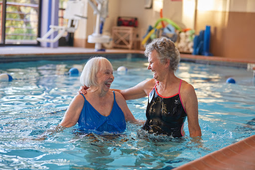 Two elderly women enjoying a joyful moment together in a swimming pool.
