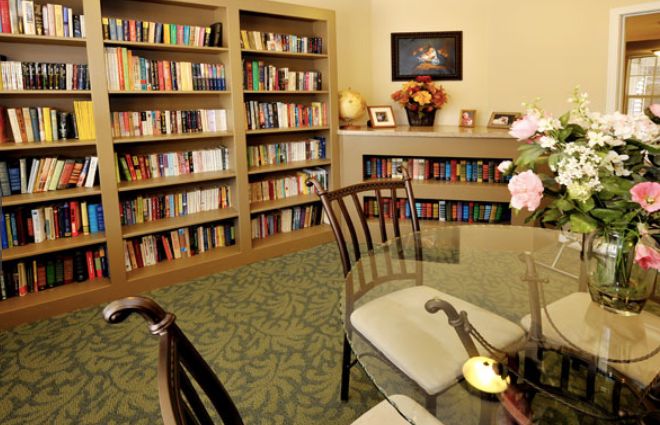 A cozy library room with bookshelves, a table, and chairs for reading.