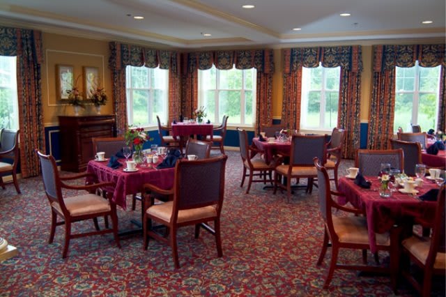 A well-decorated dining room with tables and chairs arranged neatly on a carpeted floor.