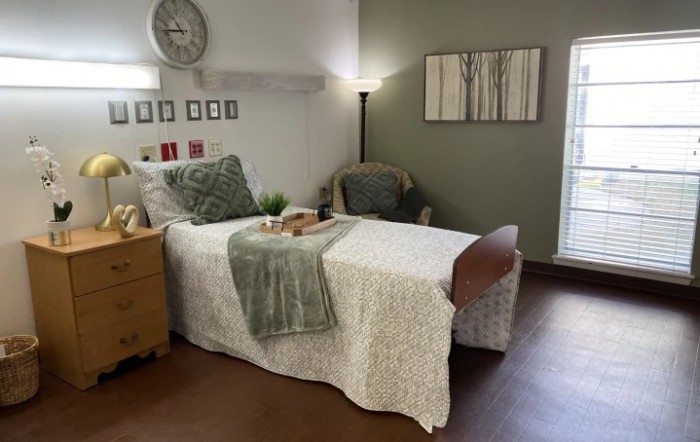 A cozy and well-decorated bedroom with a single bed, nightstand, lamp, and wall art.