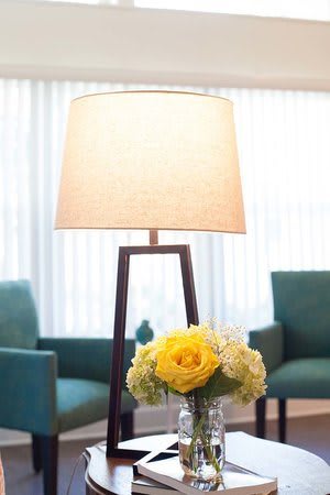 A cozy living room with a stylish lamp and a vase of yellow flowers.