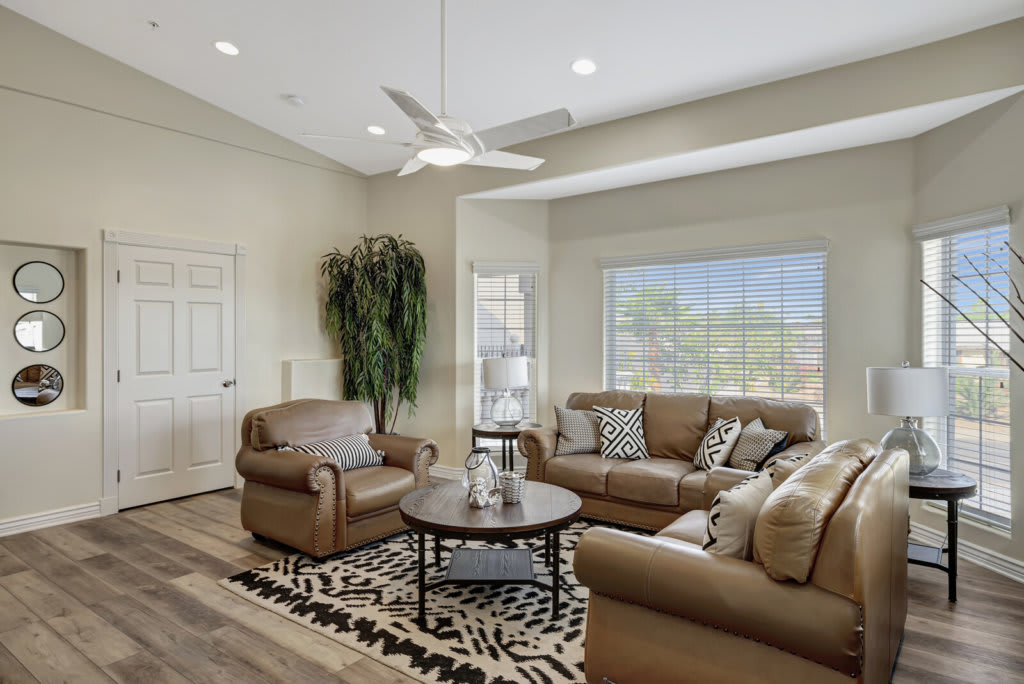 A cozy living room featuring leather sofas, a coffee table, and a large window allowing for natural light.