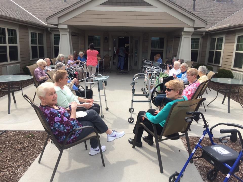 A group of elderly people sitting outside on a patio, enjoying each other's company.