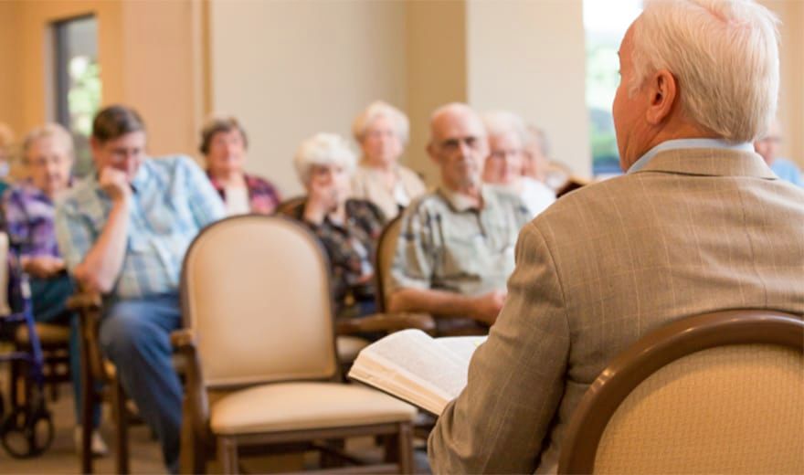 A group of elderly people attentively listening to a speaker during a community meeting.