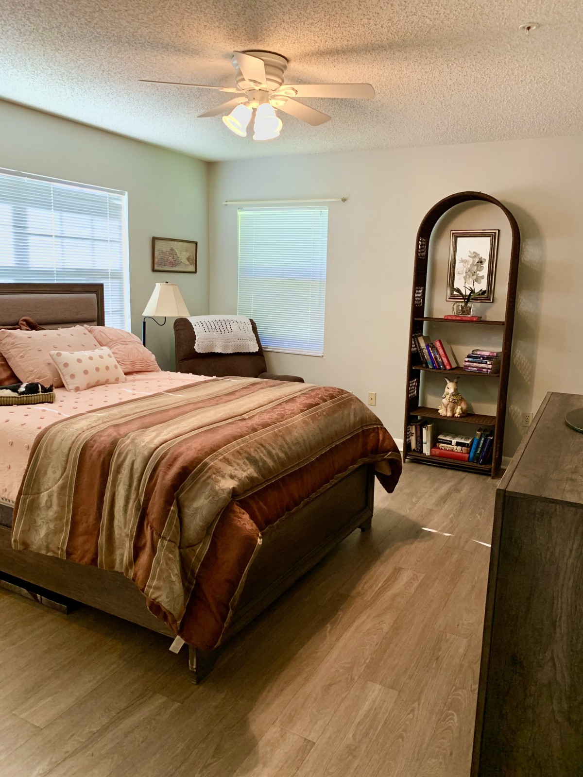 A cozy bedroom with a neatly arranged bed and a bookshelf.